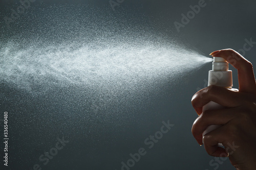 Close-up view of human hand and antiseptic spray bottle on dark background. Control Epidemic Prevention measures of coronavirus. photo