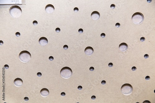 The background of the sound-absorbing plate is gray with a solid scattering perforation in the form of holes of different diameters, construction, texture, design.