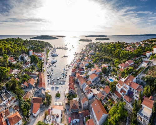 Fototapeta Naklejka Na Ścianę i Meble -  Croatia, Maslinica, 15 September 2019: Drone view point on moored in an equal row sailboats at sunset, participant of a sailing regatta, people have a rest after racing day, azure water, pier
