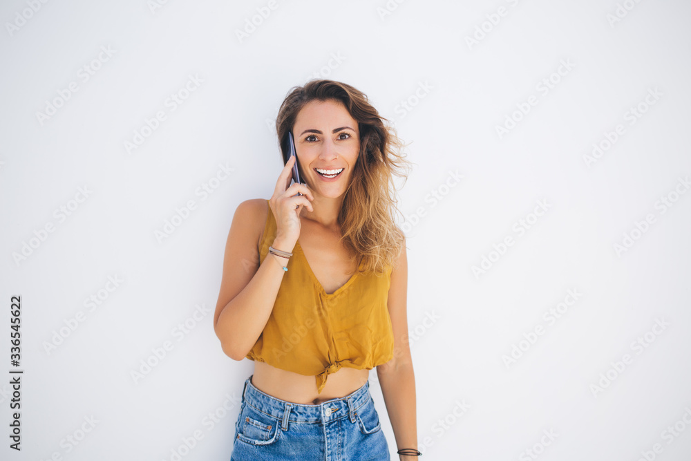 Excited woman with smartphone smiling at wall Excited woman with smartphone smiling at wall