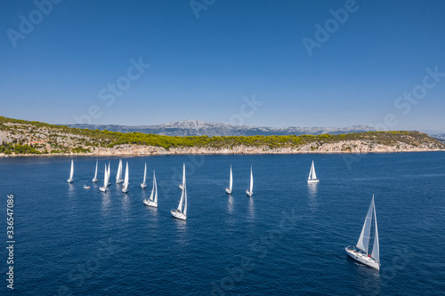 Aerial shot of the yacht race, a sailing regatta, intense competition, a lot of white sails, island is on background, top travel destination, vacation in Croatia, idyllic landscape