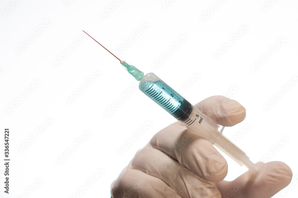Hand wearing latex glove holding syringe with a medicine on white background Hand wearing latex glove holding syringe with a medicine on white background