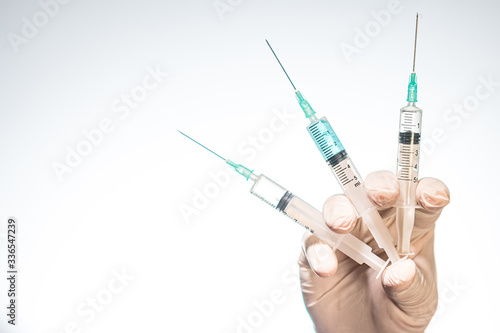 Hand wearing latex glove holding syringe with a medicine on white background