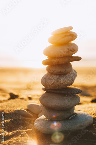 balanced stacked pebbles pyramid on beach at sunset