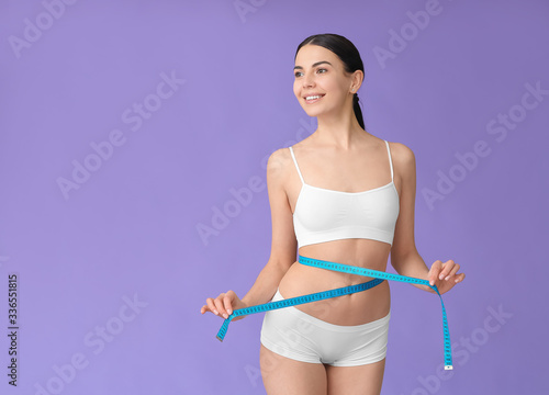 Young woman with measuring tape on color background Fototapeta