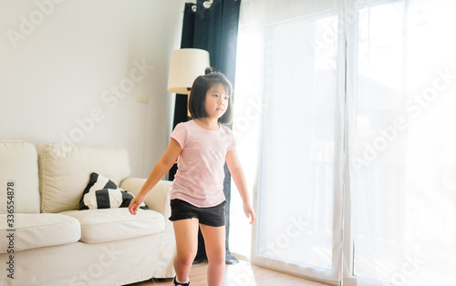 Video streaming Stay at home.home fitness workout class live streaming online.Asian little kid girl training game aerobic dance exercises watching videos on a smart tv in the living room at home.