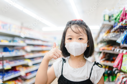 Coronavirus Covid-19 concept.Little chinese girl wearing face mask protect from virus and show stop hands gesture for stop corona virus outbreak in supermarket coronavirus and pandemic virus symptoms.