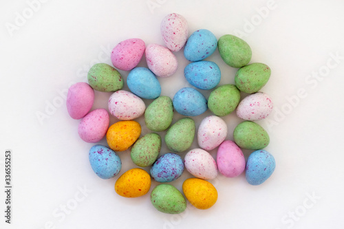 Chocolate candies in a glaze top view. Multi-colored sweets in the form of Easter eggs on a white background. Blue, yellow and green candies.
