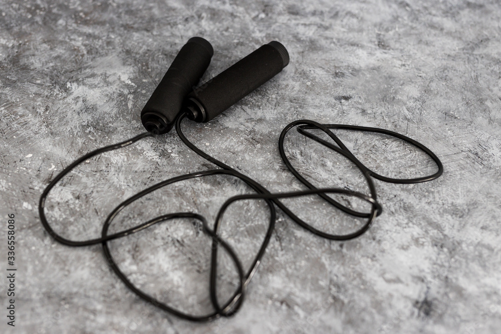 home gym gear concept, skipping rope for intense cardio workouts on concrete background home gym gear concept, skipping rope for intense cardio workouts on concrete background
