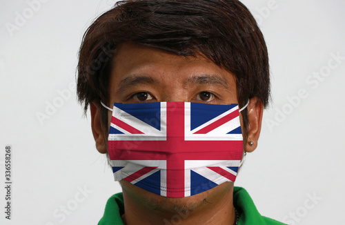 Union jack flag on hygienic mask. Masked man prevent germs and wear green shirt. Tiny Particle or Covid 19 protection. photo