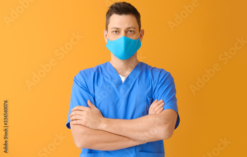 Doctor in protective medical mask on color background photo