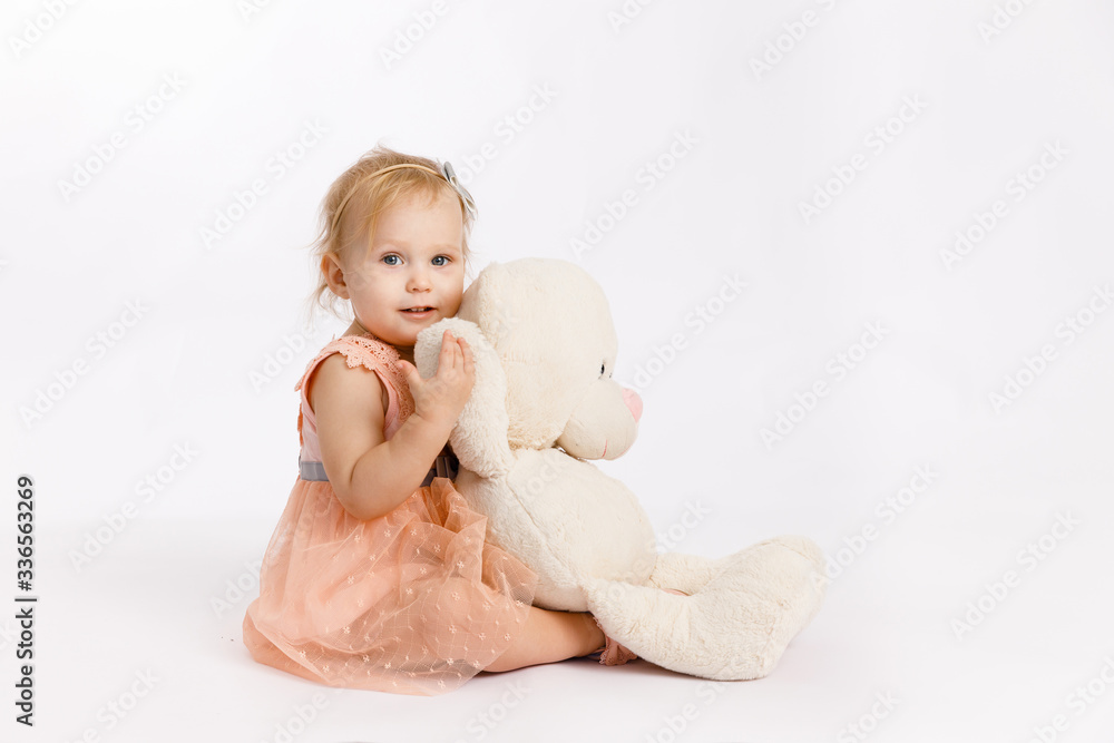 Little cute girl holds a large Teddy bear enjoy festive birthday event wear pink pastel summer dress isolated on a white background. Birthday present. Little cute girl holds a large Teddy bear enjoy festive birthday event wear pink pastel summer dress isolated on a white background. Birthday present.