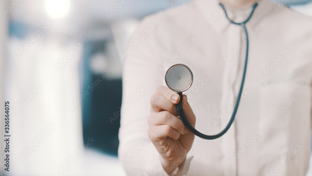 Close up of a Doctor's hand, holding a stethoscope outstretched towards the viewer. Online health consulting concept Close up of a Doctor's hand, holding a stethoscope outstretched towards the viewer. Online health consulting concept