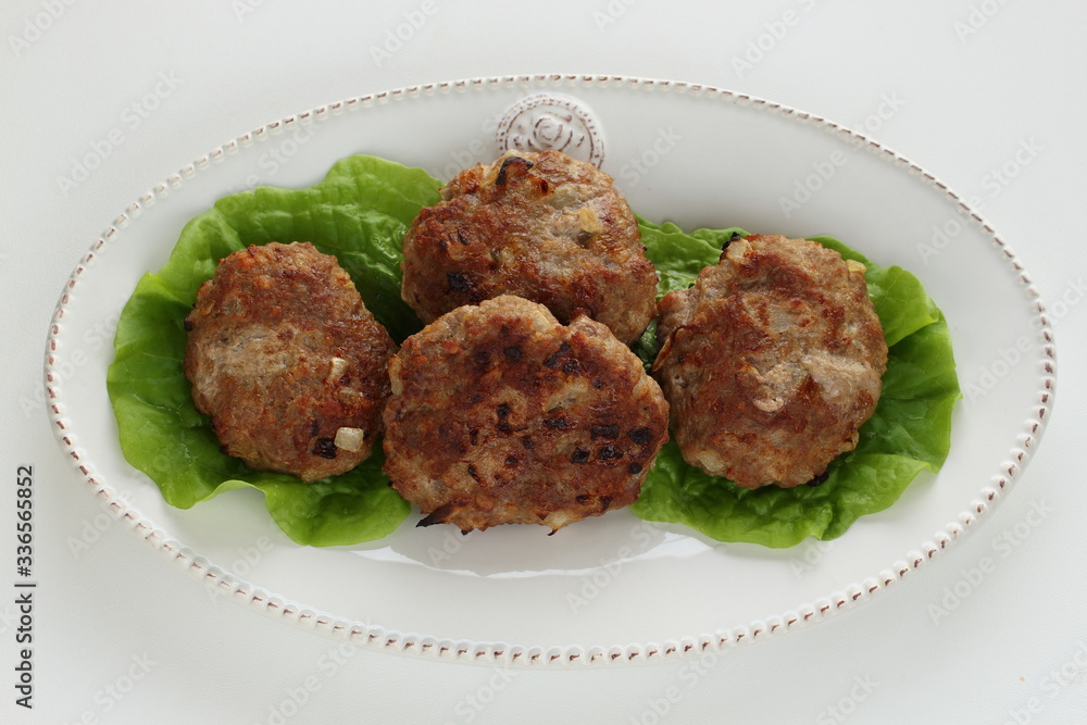 Homemade patty burger on dish with lettuce Homemade patty burger on dish with lettuce