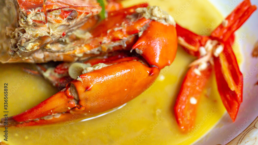 Indonesia crab curry garnished with red chili. Focus on the big claw