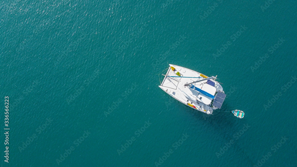 The drone captures a high angle view of catamaran sailboats moored in a tranquil bay.