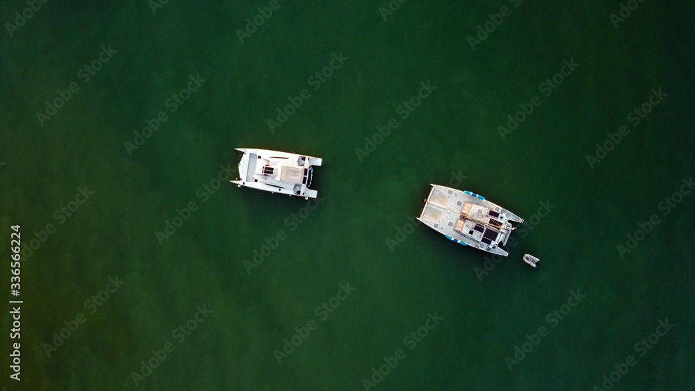 Fototapeta premium The drone captures a high angle view of catamaran sailboats moored in a tranquil bay.