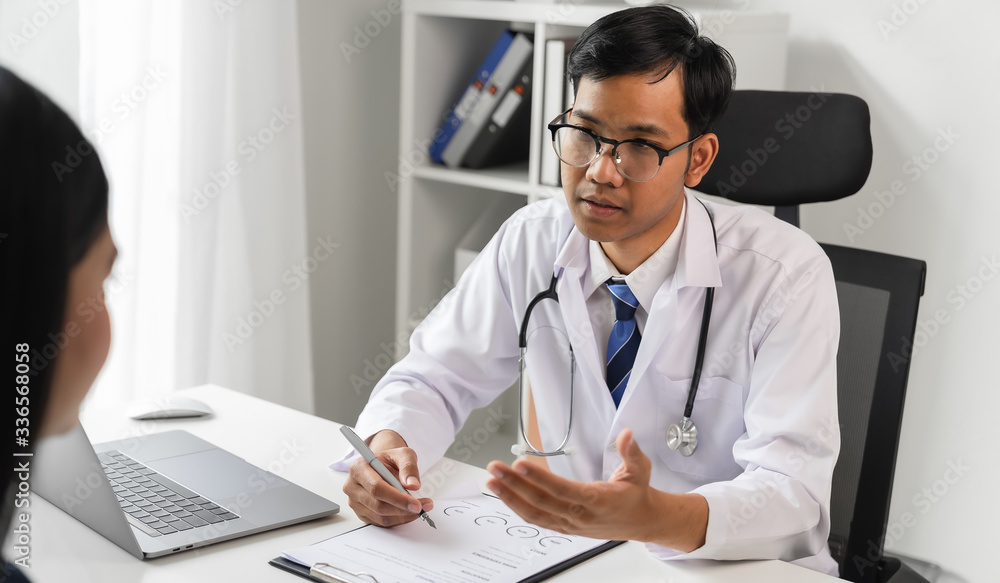 Asian doctor reports the symptoms and advises the patient. Asian doctor reports the symptoms and advises the patient.