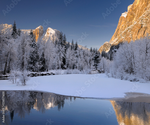 Three Brothers face and Cathedral Spires reflected in the Merced River after a snowfall in Yosemite