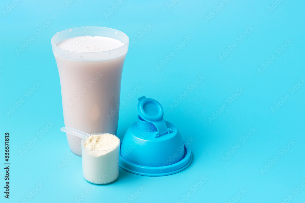 Protein shake and a scoop on blue background, copy space. Protein shake and a scoop on blue background, copy space.