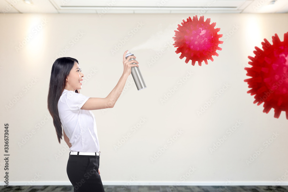 Fototapeta premium Asian businesswoman spraying disinfectant in the office room