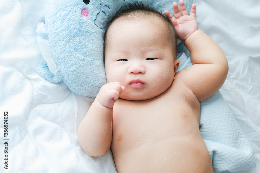 top view Portrait of a newborn Asian cute baby boy wore blue Infant bodysuit on the bed , Charming Fat baby 5 month old lies in bed with a doll,enjoy and happy top view Portrait of a newborn Asian cute baby boy wore blue Infant bodysuit on the bed , Charming Fat baby 5 month old lies in bed with a doll,enjoy and happy
