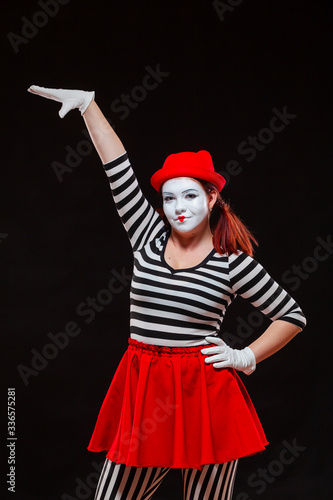 Portrait of female mime artist performing, isolated on black background. Woman raised her hand up. A symbol of growth, high interest rates, high income, large size