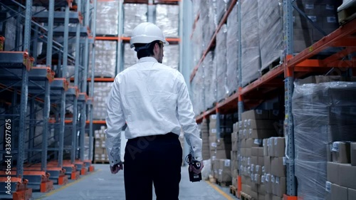 Follow footage of employees male warehouse worker engineer in hard hat working. walking through logistics center warehouse factory construction site logistics architect businessman man builder indoors