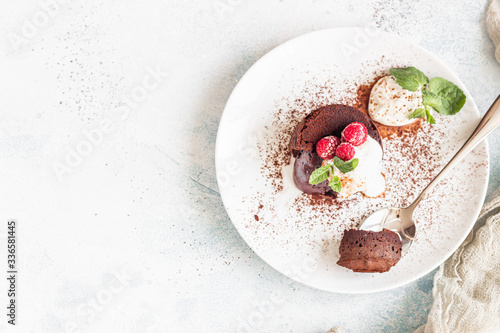Foto Delicious chocolate fondant or lava cake with cream, raspberries and cream, light grey concrete background
