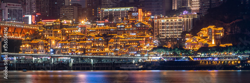Night neon ight pano view of historic traditional architecture in Hongya Dong cave by Jialing river in Chongqing, China