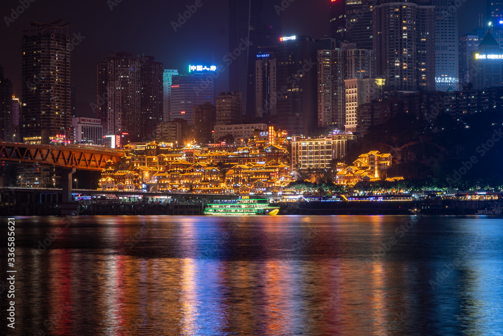 Naklejka premium Night neon ight l view of historic Hongya Dong cave by Jialing river with qian si men bridge in Chongqing, China
