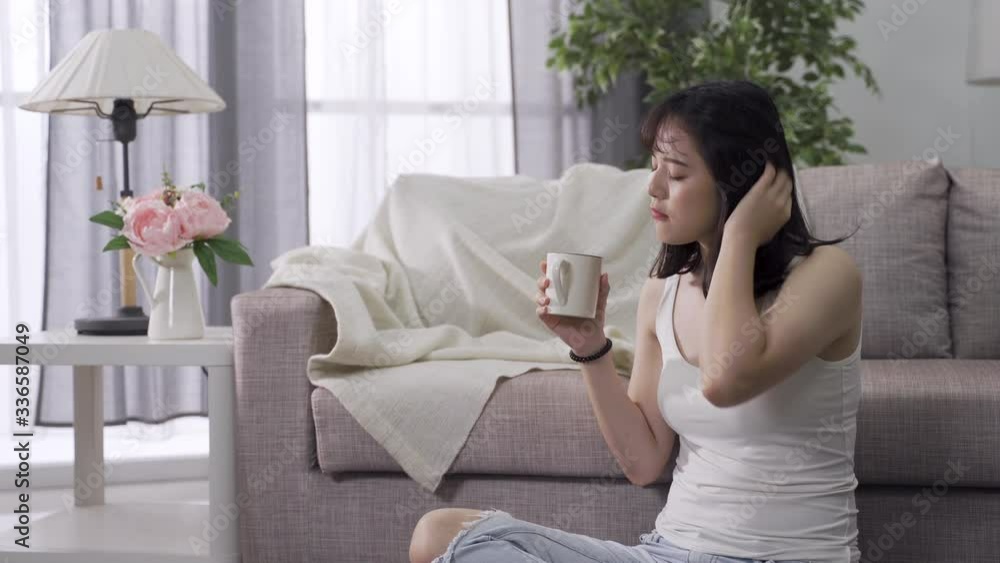 gorgeous asian lady getting up at dawn with morning coffee tries to pick up energy by stretching her body. chinese woman in casual attire combing hair with fingers feels a bit groggy in early morning