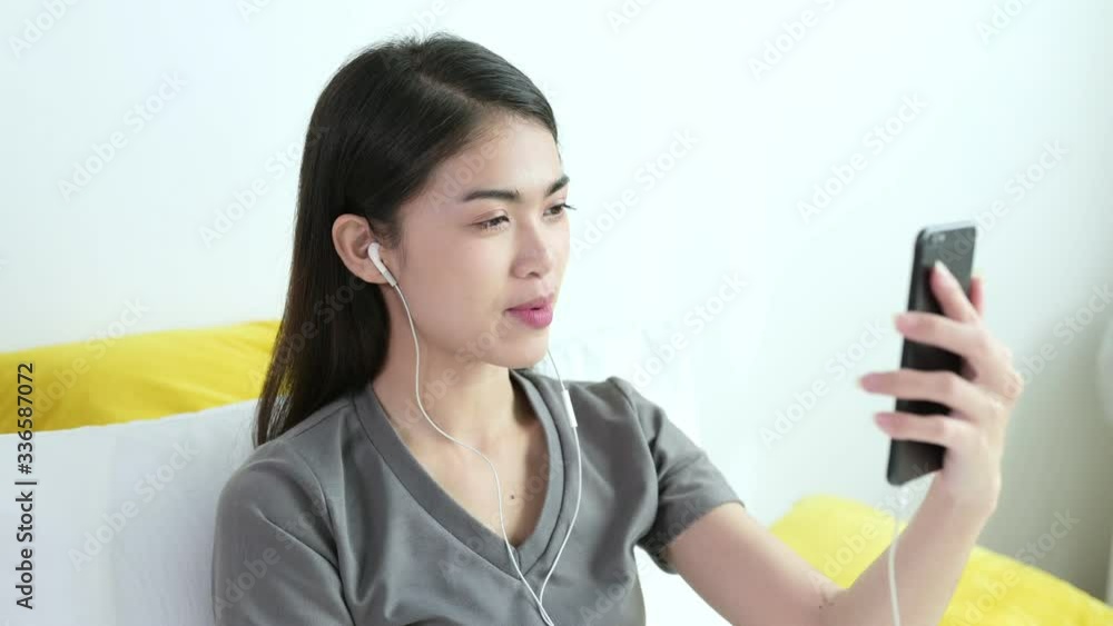 Beautiful young asian woman in grey T-shirt are video calling by mobile phone with her friend, family or boyfriend for social distancing policy. Self quarantine, coronavirus, work from home concept Beautiful young asian woman in grey T-shirt are video calling by mobile phone with her friend, family or boyfriend for social distancing policy. Self quarantine, coronavirus, work from home concept