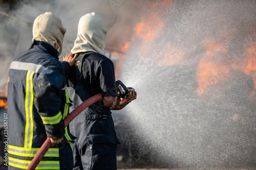 Firefighter spraying water from big water hose to prevent fire