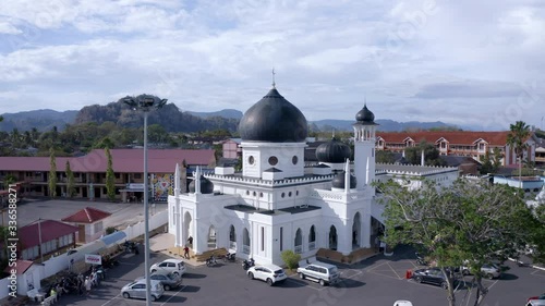 4K Aerial view of a Moorish Influence White Mosque with Black dome. Establish view of state mosque in Perlis. Push In Shot photo