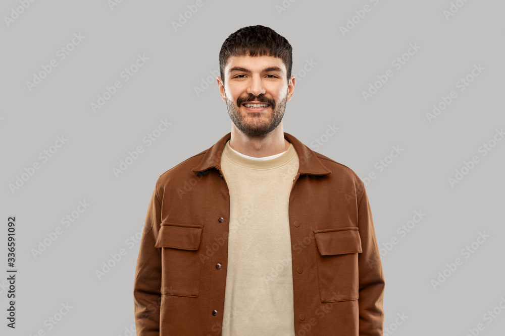 people concept - portrait of happy smiling young man with mustaches over grey background people concept - portrait of happy smiling young man with mustaches over grey background