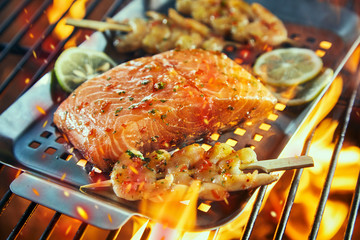 Raw salmon fillet with prawn kebabs on a fire
