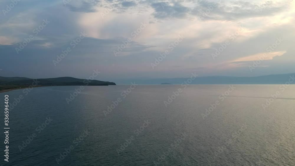 Beautiful Sunset. The drone gradually flies over the surface of the water. Lake Baikal, nature of Russian Federation. Blue crystal water. Aerial Video Shot. Beautiful Sunset. The drone gradually flies over the surface of the water. Lake Baikal, nature of Russian Federation. Blue crystal water. Aerial Video Shot.