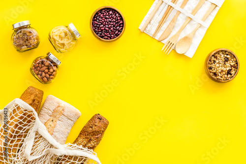 Glass jars, cotton bags on yellow background, top view. Eco friendly concept for kitchen - food storage copy space