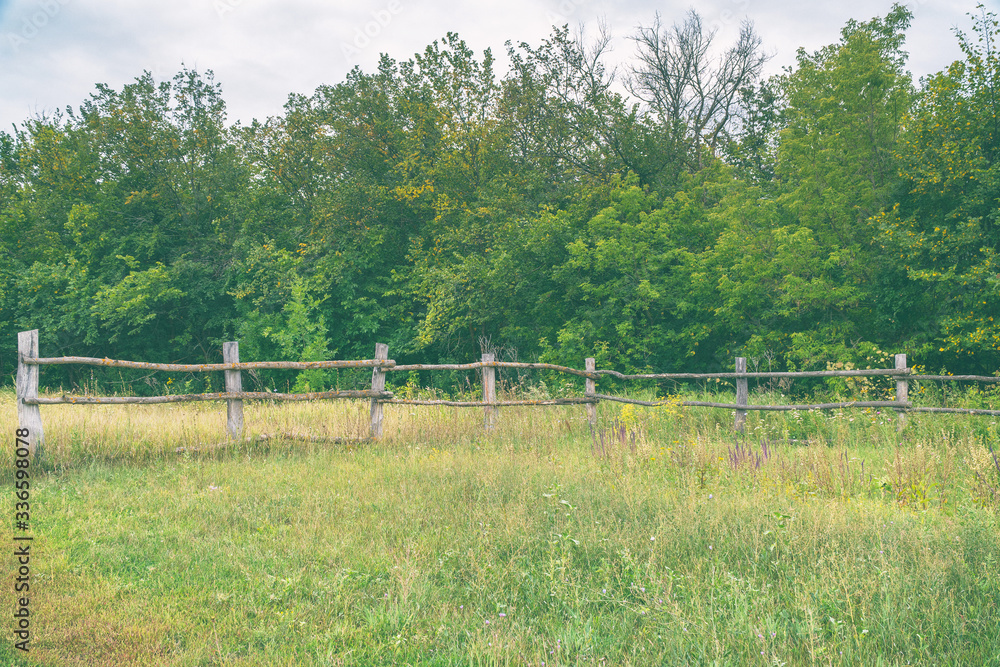 Primitive rustic wooden fence in front of the forest Primitive rustic wooden fence in front of the forest