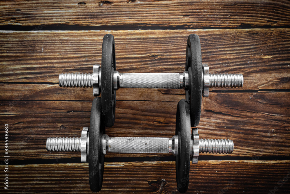 Black collapsible dumbbells on wooden background Black collapsible dumbbells on wooden background
