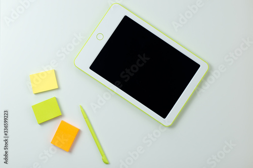 White tablet with pen and sticky notes on white table. Home office while self-isolation, working from home. Online education, e-learning while quarantine.