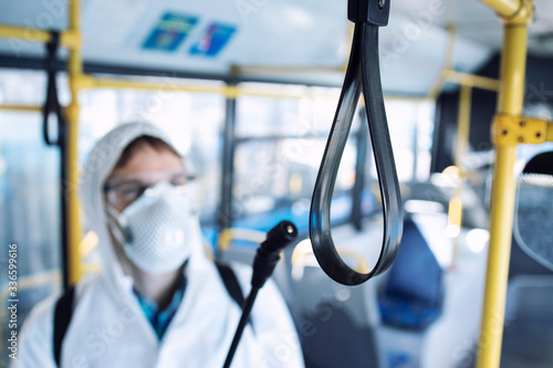 Disinfecting passenger handlebars of public bus transportation to stop spreading highly contagious coronavirus or COVID-19.