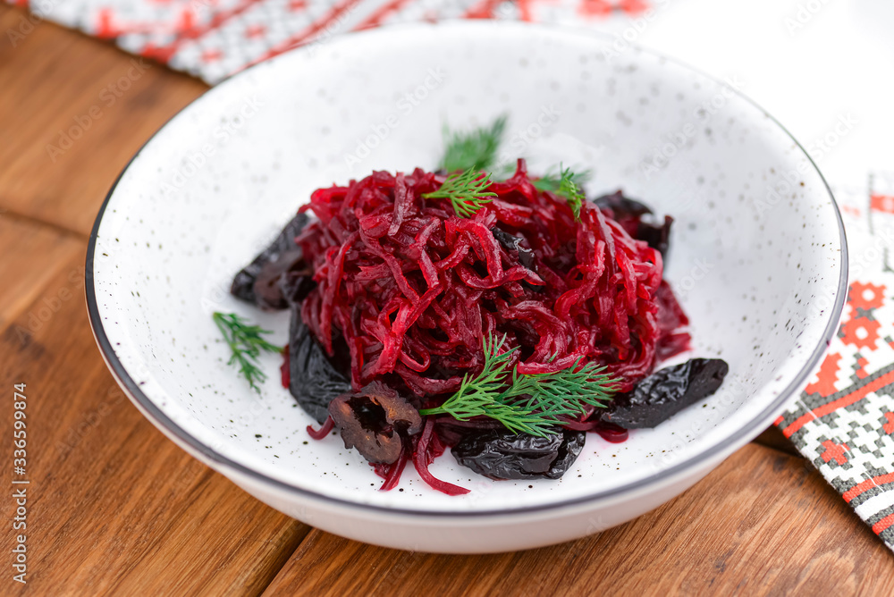 Traditional Ukrainian beetroot salad served in white bowl over rustic wooden table with traditional tablecloth. Traditional Ukrainian beetroot salad served in white bowl over rustic wooden table with traditional tablecloth.