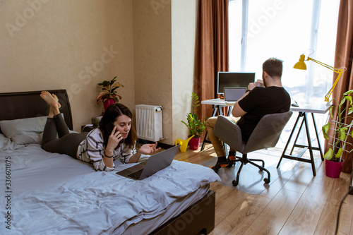 couple working at home. home isolation. woman on bed. man at office chair