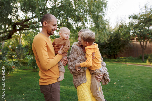 
family in nature, summer or autumn, green grass trees in green leaves, a pond in nature, mom blonde in a yellow dress, dad, husband, older son and youngest son, two children, a large and happy family