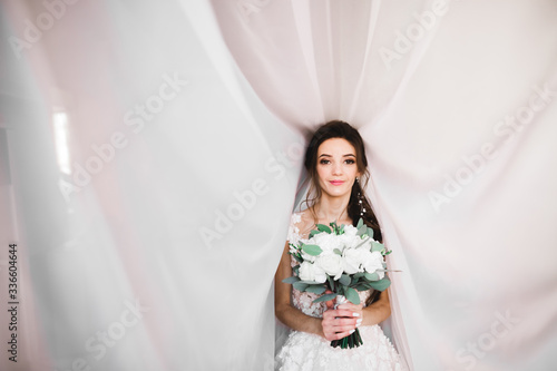 Luxury bride in white dress posing while preparing for the wedding ceremony