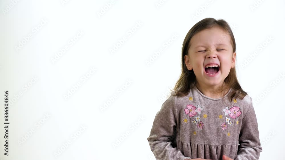 Little beautiful girl laughing and looks at the camera on white wall background Little beautiful girl laughing and looks at the camera on white wall background