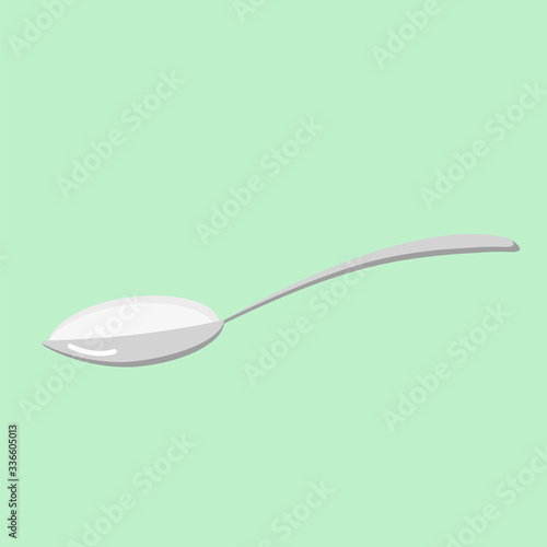 Spoon with white powder on a light green background.