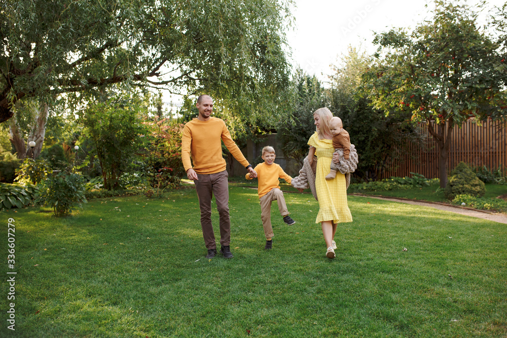 Obraz premium family in nature, summer or autumn, green grass trees in green leaves, a pond in nature, mom blonde in a yellow dress, dad, husband, older son and youngest son, two children, a large and happy family